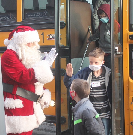 Santa waving at students getting off bus