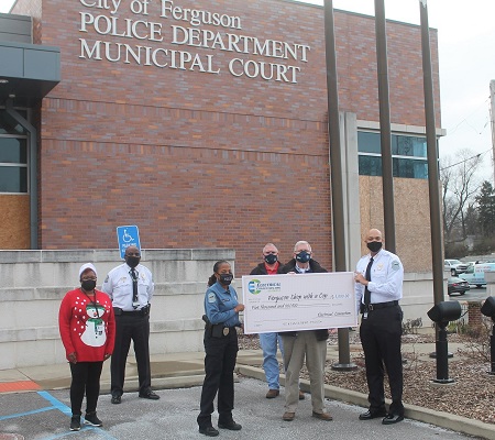 People in masks posing with a check in front of the Ferguson Police Department