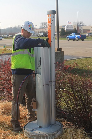 Man in hard hat installing electric vehicle charging station