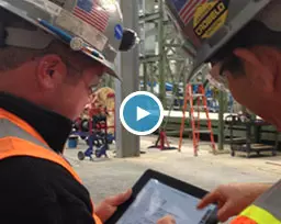 men in hard hats looking at tablet